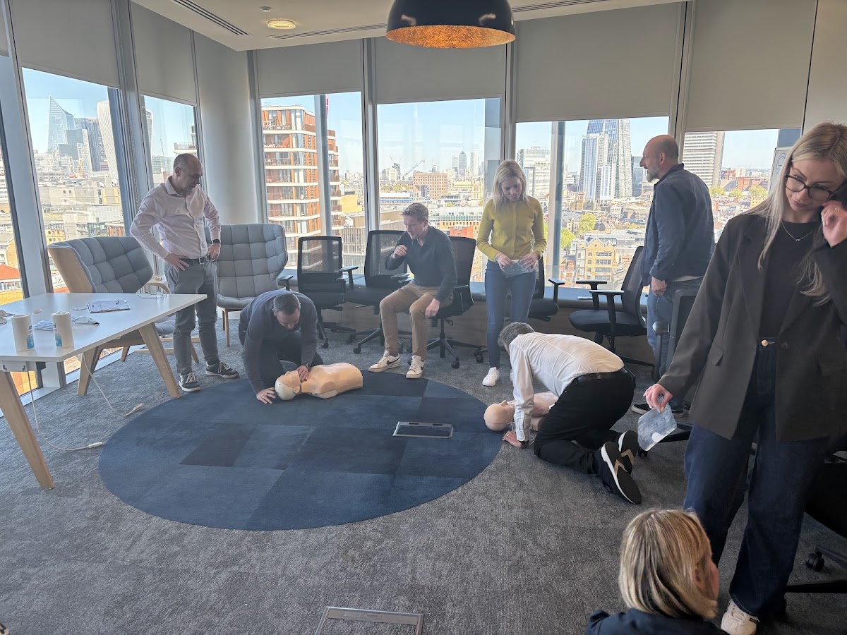 Group practising CPR on manikins in modern London office